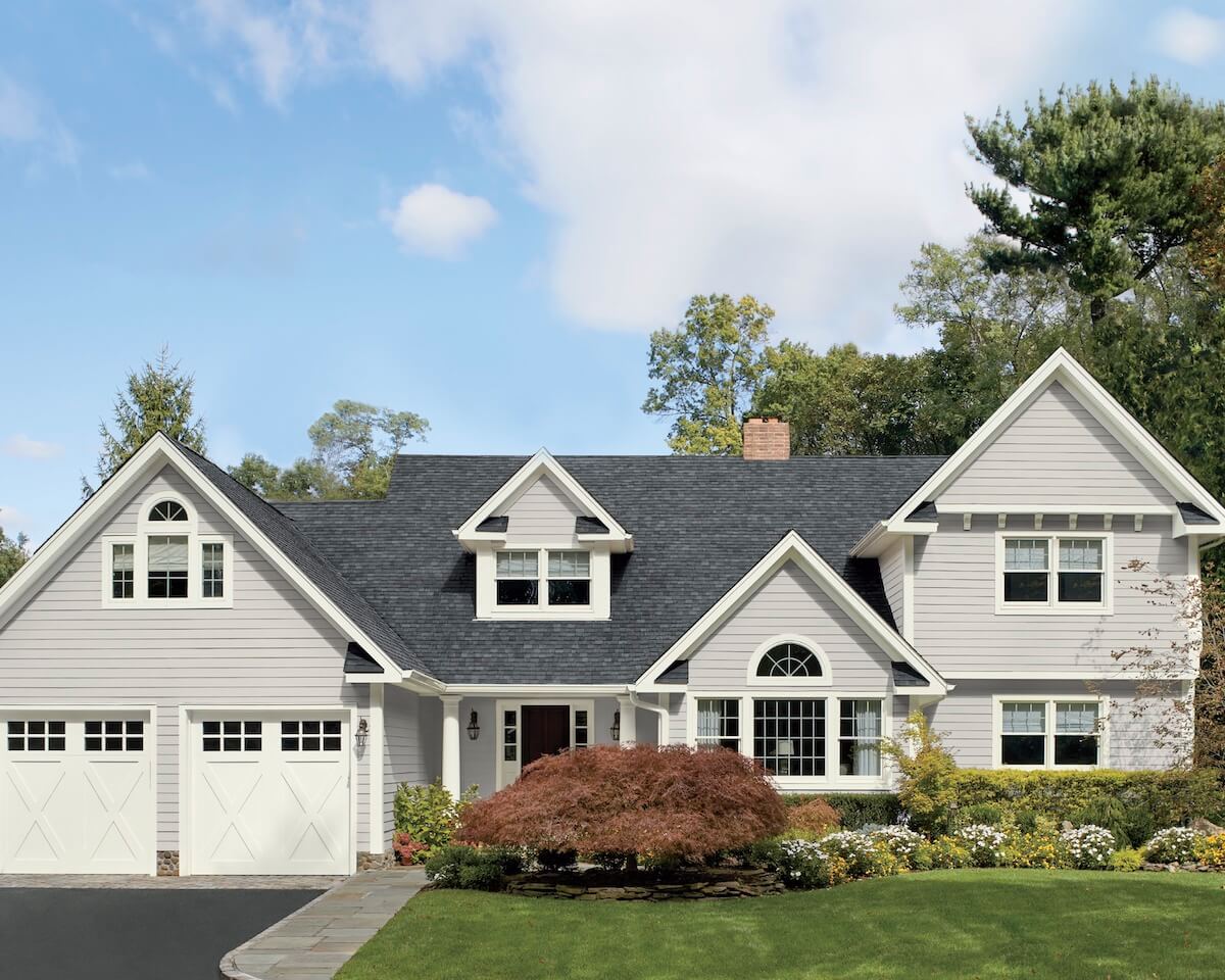 A light gray coloured house with vinyl siding and two door garage.